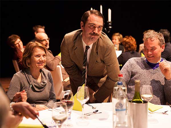 Basil leaning over audience table