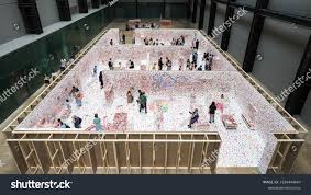 Top-down shot of Obliteration Room. It appears mostly white, visitors walk through it. You can see the outsides of the bounding wall, which are bare plywood. The whole room is contained within a warehouse.